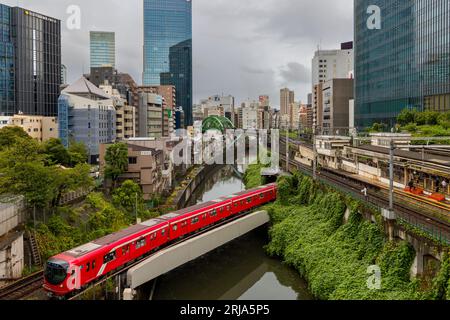 TOKIO, JAPAN - 9. AUGUST 2023: Züge, die an einer vielbefahrenen Kreuzung und einem Tunnel über den Kanda River an der Hijiribashi-Brücke in Tokio, Japan, vorbeifahren Stockfoto