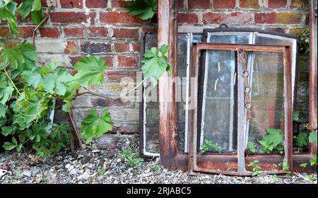 Ein Paar Vintage-Fensterrahmen und alte Fenster gegen eine Mauerwerkwand. Ein rustikales Bild von alten Materialien vor einer Ziegelmauer. Stockfoto