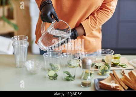 Nahaufnahme des Café-Mitarbeiters, der Mineralwasser in Limonadengläser gießt und erfrischende Getränke serviert, Kopierraum Stockfoto