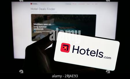 Person holding smartphone with logo of US hotel booking company Hotels.com LP on screen in front of website. Focus on phone display. Stock Photo