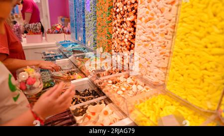 Plastikgläser gefüllt mit bunten Süßigkeiten im Geschäft. Stockfoto