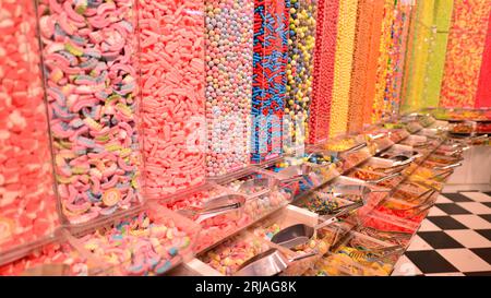 Plastikgläser gefüllt mit bunten Süßigkeiten im Geschäft. Stockfoto