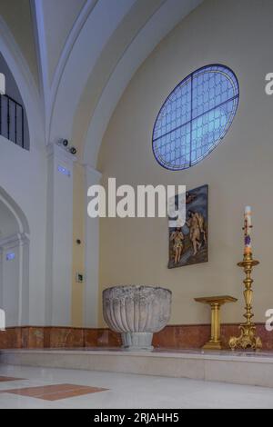 Baptisterium: Taufbecken, romanischer Stil, österliche Kerze und hohes Relief aus Holz der Taufe Jesu durch den Heiligen Johannes den Täufer, Guadalajara Stockfoto