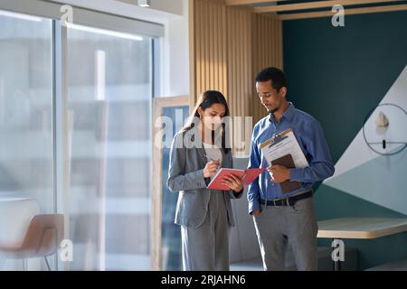 Zwei multikulturelle Arbeiter, die im Amt über den Arbeitsplan des Unternehmens diskutieren. Stockfoto