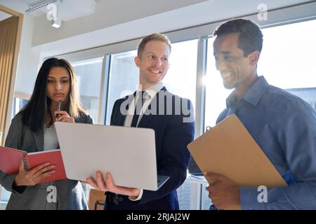 Mitarbeiter des internationalen Business Teams, die im Büro mit einem Laptop arbeiten. Stockfoto