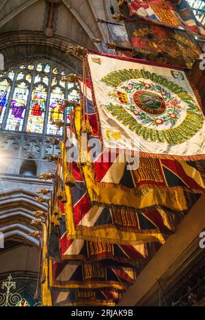 Britische Regimentsflaggen hängen im südlichen Querschiff der Lichfield Cathedral in Staffordshire, Großbritannien. Die Flaggen, die Kampfehren auflisten, sind es Stockfoto