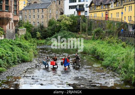 Edinburgh, Schottland, Großbritannien. August 2023. Edinburgh Fringe: Home, die Show zeigt die Klimakrise und wie Überschwemmungen die Fens in East Anglia betreffen. Schauspieler mit Requisiten im Wasser von Leith im Dean Village. Im Pleasance Courtyard zu sehen. Bildunterschrift, die teilweise aus der offiziellen Pressemitteilung erstellt wurde. Credit Craig Brown/Alamy Live News Stockfoto