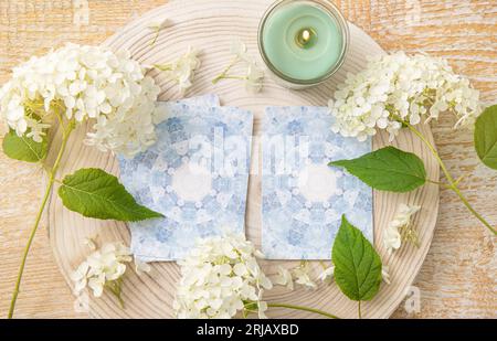 Deck mit hausgemachten Wahrsagungsengel-Karten auf Holztisch mit Hortensienblume zur Dekoration. Zu Hause brennen Kerzen. Stockfoto