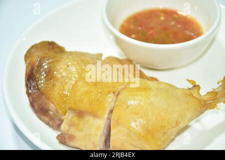 boiled chicken thigh and leg with herb brown soup on plate dipping spicy chili sauce cup Stockfoto