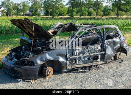 Verbranntes, zerstörtes Auto nach einer Explosion am Straßenrand Stockfoto