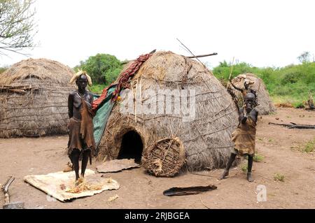 Menschen und traditionelle Hütten im Dorf Mursi. Debub Omo Zone, Äthiopien. Stockfoto