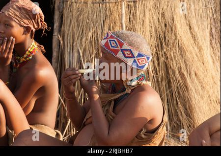 Buschleute oder san-Frau raucht vor seiner Hütte. Tsumkwe, Otjozondjupa, Kalahari, Namibia. Stockfoto