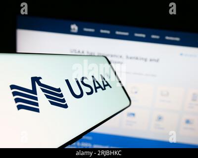 Mobile phone with logo of United Services Automobile Association (USAA) on screen in front of website. Focus on center-left of phone display. Stock Photo