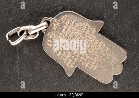 One metal keyring, Jewish 'Hand of Miriam' on slate stone, close-up, top view. Road prayer. Stock Photo
