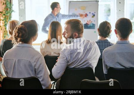 Rückansicht des Motivationslautsprechers mit Headset und Whiteboard auf der Bühne. Symposium über Wirtschaft und Unternehmertum. Stockfoto