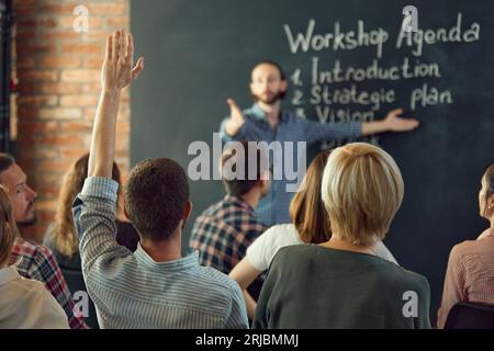 Der freundliche Business Coach kommuniziert mit einer Gruppe erwachsener Studenten auf einem Business-Seminar im Tagungsraum. Stockfoto