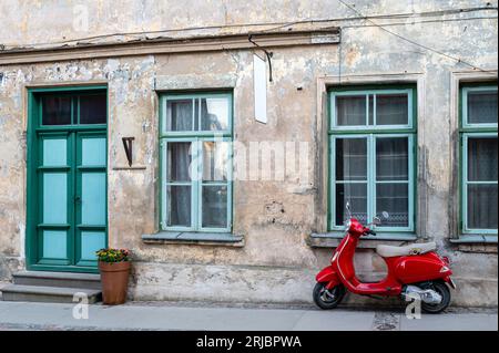 Ein roter Oldtimer auf einem Fußgängerweg vor einem alten Steinhaus Stockfoto