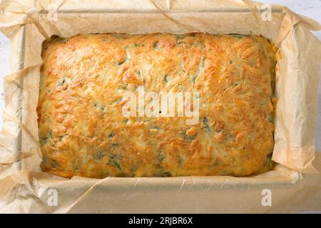 Frisch gebackener Kuchen mit Spinat, Sauerampfer und Käse in einer Backform mit Pergament, Blick von oben. Schritt für Schritt kochen. Stockfoto