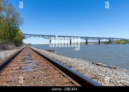 Poughkeepsie, NY, USA-Mai 2022; Blick auf Eisenbahnschienen am Hudson River mit in Distance dem 1,28 Miles Walkway über den Hudson State Historic Park Stockfoto