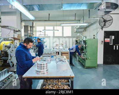 Mitarbeiter, die in einer Etikettendruckerei arbeiten. Der Arbeiter verwendet eine Etikettiermaschine. Aufkleberdrucker. Druckmaschine, die an Etiketten arbeitet. Stockfoto