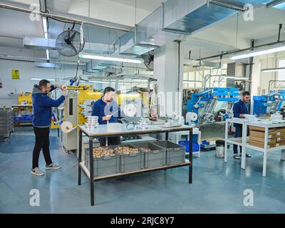 Mitarbeiter, die in einer Etikettendruckerei arbeiten. Der Arbeiter verwendet eine Etikettiermaschine. Aufkleberdrucker. Druckmaschine, die an Etiketten arbeitet. Stockfoto