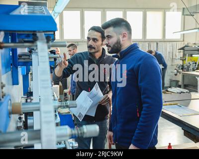 Mitarbeiter, die in einer Etikettendruckerei arbeiten. Der Arbeiter verwendet eine Etikettiermaschine. Aufkleberdrucker. Druckmaschine, die an Etiketten arbeitet. Stockfoto