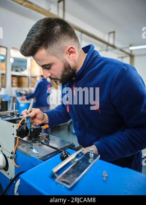 Mitarbeiter, die in einer Etikettendruckerei arbeiten. Der Arbeiter verwendet eine Etikettiermaschine. Aufkleberdrucker. Druckmaschine, die an Etiketten arbeitet. Stockfoto