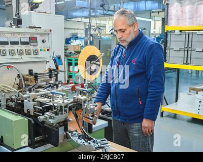 Mitarbeiter, die in einer Etikettendruckerei arbeiten. Der Arbeiter verwendet eine Etikettiermaschine. Aufkleberdrucker. Druckmaschine, die an Etiketten arbeitet. Stockfoto