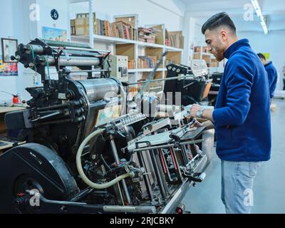 Mitarbeiter, die in einer Etikettendruckerei arbeiten. Der Arbeiter verwendet eine Etikettiermaschine. Aufkleberdrucker. Druckmaschine, die an Etiketten arbeitet. Stockfoto