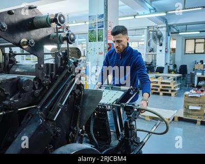 Mitarbeiter, die in einer Etikettendruckerei arbeiten. Der Arbeiter verwendet eine Etikettiermaschine. Aufkleberdrucker. Druckmaschine, die an Etiketten arbeitet. Stockfoto