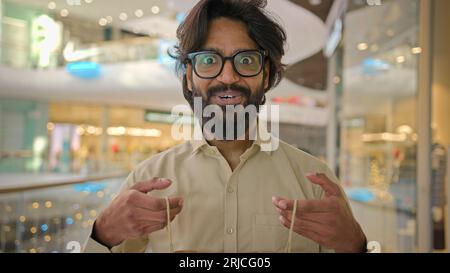 Indianer begeistert glücklich überrascht fröhlicher Mann Käufer Kunde Geschäftsmann Araber bärtiger Mann in Gläsern offene Verpackung Einkaufstasche mit Blick nach innen Stockfoto