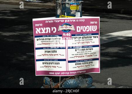 A bilingual sign from the Pupa Hasidic group listing lectures on the upcoming Sabbath's torah readings. On Lee Avenue in Williamsburg, Brooklyn, NYC. Stock Photo