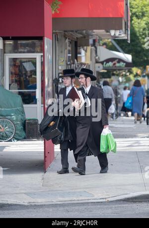 STRASSENSZENE. Zwei ähnlich gekleidete chassidische Juden biegen an der Lee Avenue in Williamsburg, Brooklyn, New York ab. Stockfoto