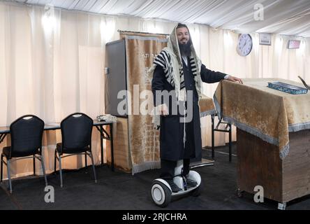 A sexton - shammash - at a synagogue with a few tents. His hoverboard lets him be everywhere at once. In Mosey, New York. Stockfoto