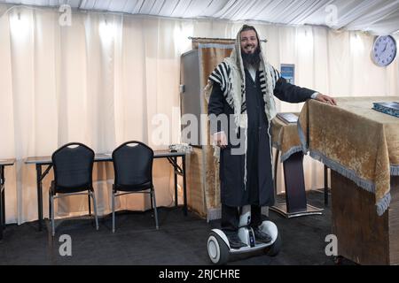 A sexton - shammash - at a synagogue with a few tents. His hoverboard lets him be everywhere at once. In Mosey, New York. Stockfoto
