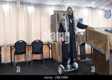 A sexton - shammash - at a synagogue with a few tents. His hoverboard lets him be everywhere at once. In Mosey, New York. Stockfoto