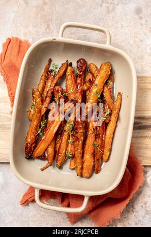 Geröstete Karotten mit Thymian, Knoblauch, Zitrone und Honig auf Backblech. Gesundes Wurzelgemüse-Konzept Stockfoto
