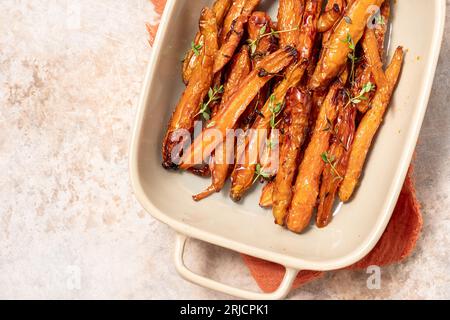 Geröstete Karotten mit Thymian, Knoblauch, Zitrone und Honig auf Backblech. Gesundes Wurzelgemüse-Konzept Stockfoto