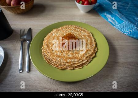Pfannkuchen mit Cloudberry Jam auf einem grünen Teller auf einem Holztisch Stockfoto