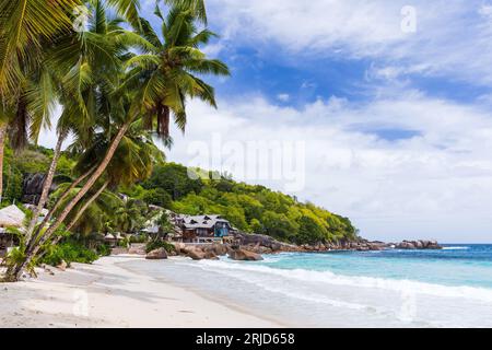 Blick auf den Strand von Anse Takamaka mit Palmen und weißem Sand unter bewölktem Himmel an einem sonnigen Tag. Mahe Island, Seychellen Stockfoto