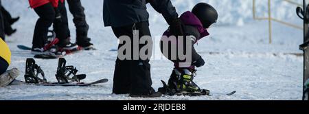 Eine Instruktorin unterrichtet einen Jungen, wie man auf einer schneebedeckten Berghänge Ski fährt Stockfoto