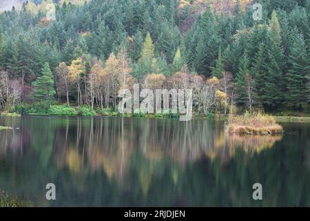 Herbstfarben auf Bäumen spiegeln sich in einem Loch an in Glencoe, Lochaber, Schottland, Großbritannien Stockfoto
