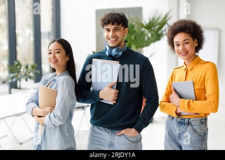 Studentschaft. Glückliche internationale Studenten posieren im modernen Publikum, verschiedene junge Menschen stehen im Klassenzimmer Stockfoto