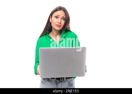 Süße junge, braunäugige, braunhaarige Karrierefrau mit Make-up in einer grünen Bluse arbeitet Remote im IT-Bereich Stockfoto