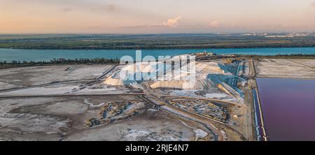 Panoramalandschaft mit rosafarbenen Salzpfannen und Salzpfählen am Salin de Giraud in der Camargue, Provence, Südfrankreich bei Sonnenuntergang Stockfoto