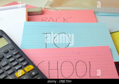 Ein Foto der Worte „zurück zur Schule“ auf farbigen Karteikarten auf einem Schreibtisch mit Taschenrechnern, Gummis und Ordnern. Stockfoto