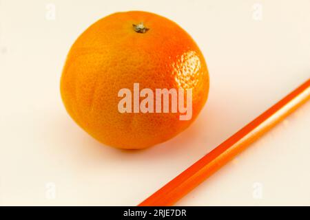 Ein Foto einer Orange neben einem Bleistift auf einem weißen Schreibtisch. Stockfoto