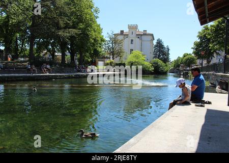 Vater und Sohn entspannen sich am Ufer des Flusses Sorgue an einem warmen Frühlingstag in L'Isle sur la Sorgue. Konzept für entspannende Einheimische, abkühlende Touristen Stockfoto