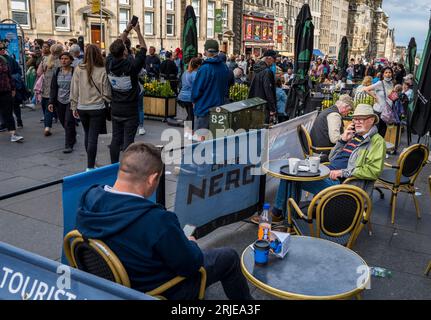 Eine Szene in Edinburghs Royal Mile während der letzten Woche des Edinburgh Festival Fringe 2023. Leute, die die Café-Szene auf der Royal Mile genießen. Stockfoto