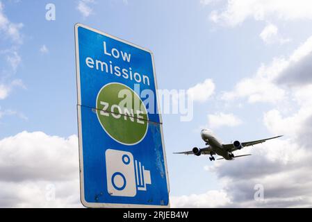 Schild für emissionsarme Zonen mit Landung eines Düsenflugzeugs am Flughafen London Heathrow, Großbritannien. Luftverschmutzung. Kohlendioxidemissionen. Luftverkehrsemissionen. Kamerabild Stockfoto